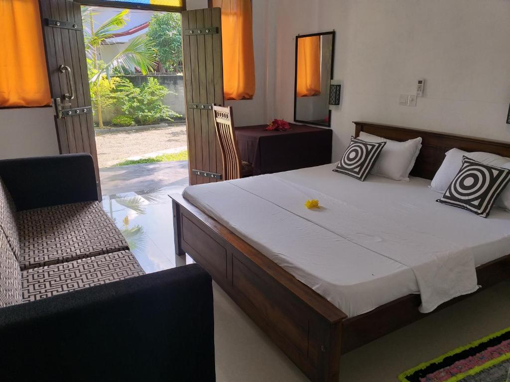 مای داخلی یک اتاق خواب با تخت دو نفره چوبی، بالشت‌های طرح‌دار، کاناپه مشکی و درهای باز چوبی که به یک حیاط سرسبز باز می‌شوند.