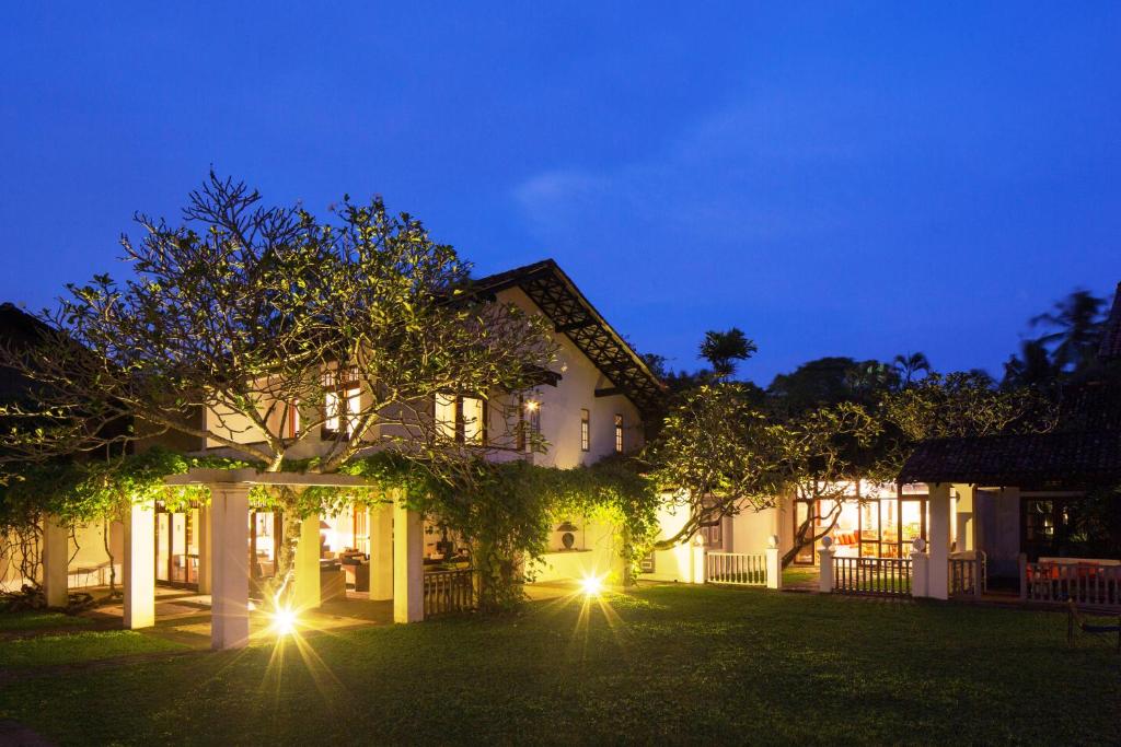 نمای بیرونی یک ویلای لوکس و مدرن در شب با نورپردازی گرم، محوطه سرسبز چمن‌کاری شده و درختان تزئینی در حیاط.